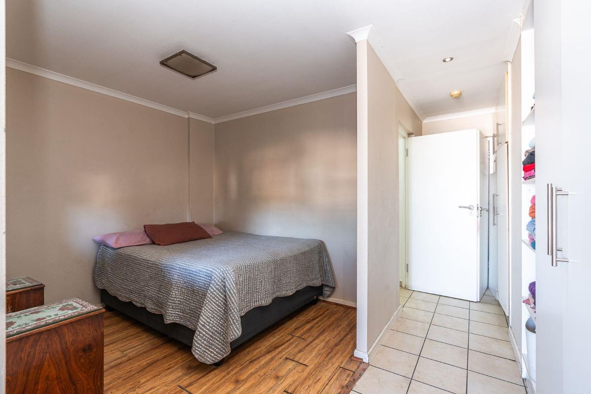 Bedroom featuring a combination of laminate and tiled flooring, built-in cupboards, and recessed lighting, providing a functional and practical living space.