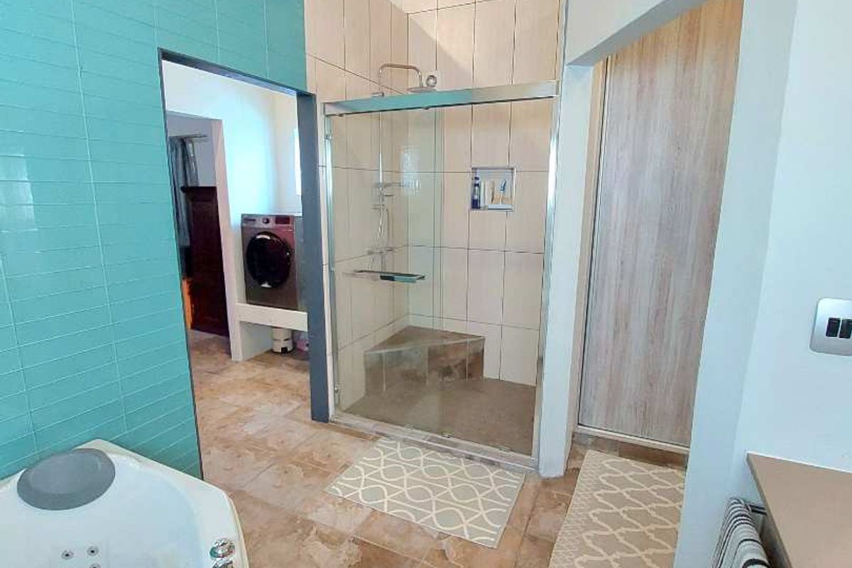 A modern bathroom featuring a corner jetted tub, a glass-enclosed walk-in shower with tiled walls, and a vaulted timber ceiling.
