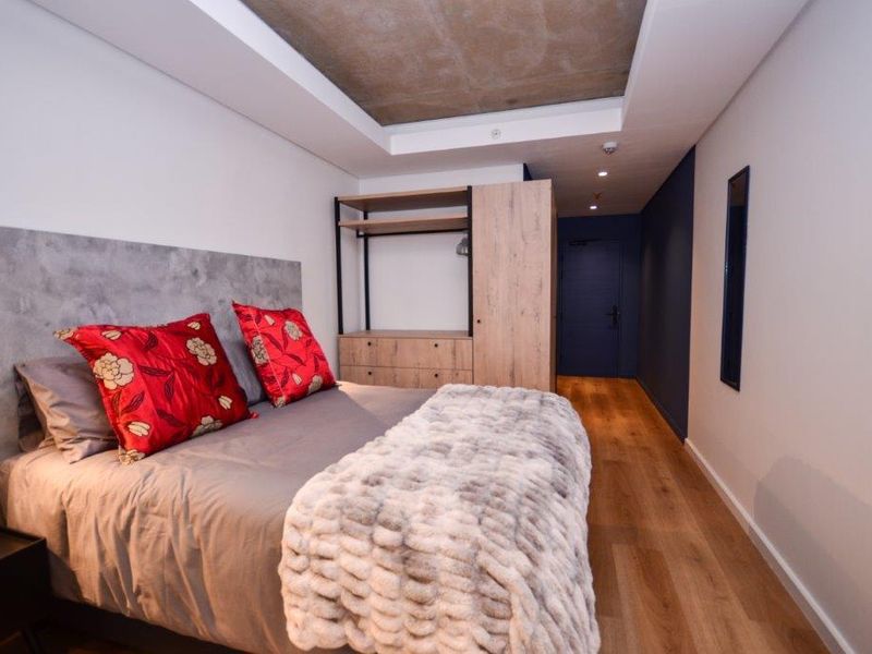 Modern bedroom featuring a recessed ceiling, laminate flooring, and a built-in wardrobe with a sleek, contemporary design.