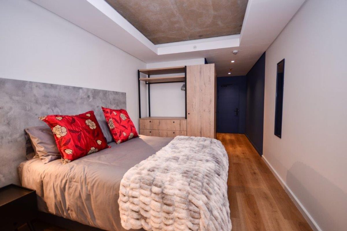 Modern bedroom featuring a recessed ceiling, laminate flooring, and a built-in wardrobe with a sleek, contemporary design.
