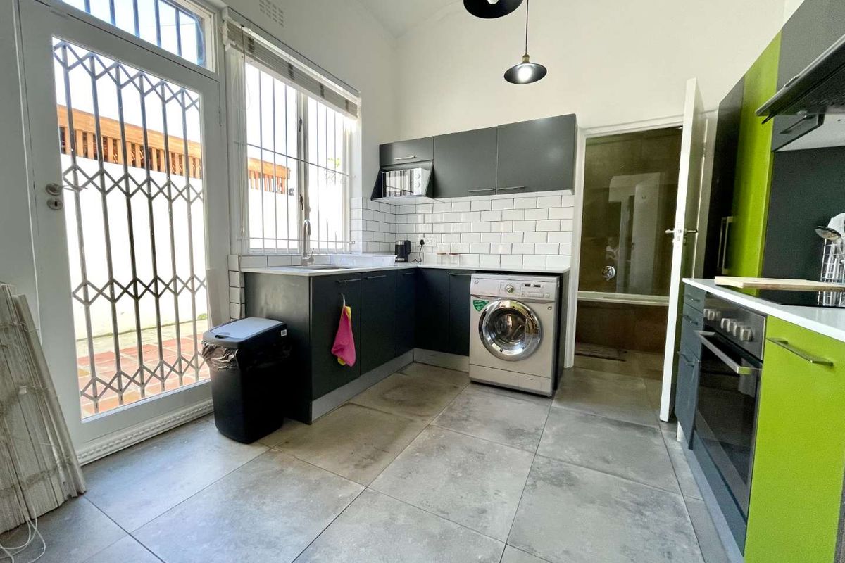 Modern kitchen featuring dark cabinetry, subway tile backsplash, integrated appliances, and direct access to the exterior through a security-gated door.