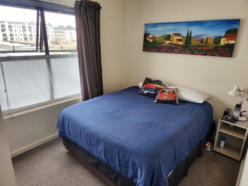 A standard bedroom featuring carpeted flooring and a large window with natural light, providing a functional living space.
