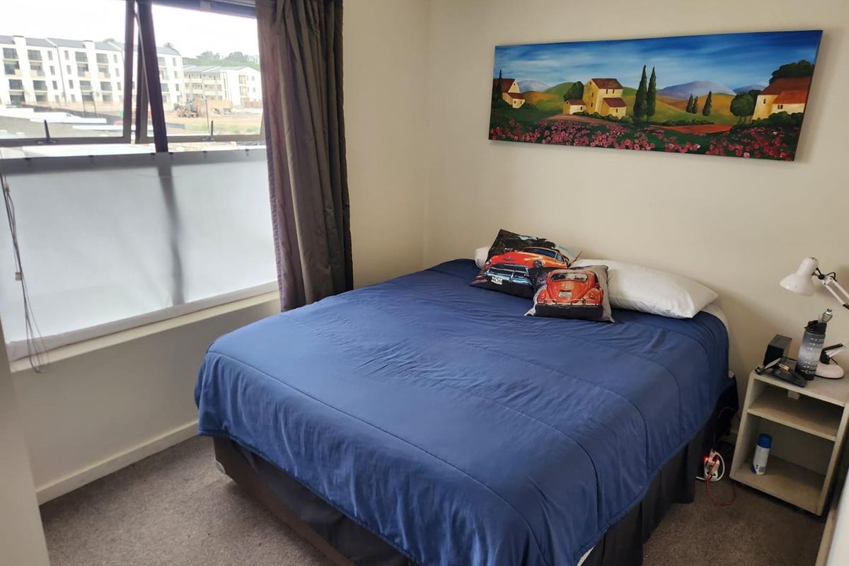 A standard bedroom featuring carpeted flooring and a large window with natural light, providing a functional living space.