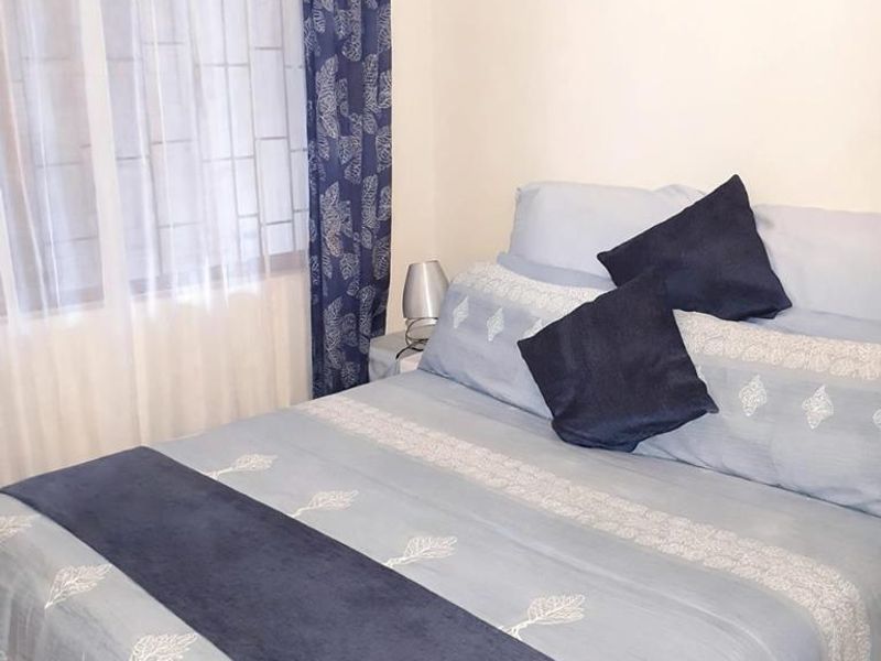A cozy bedroom featuring a window with security bars, providing natural light and a secure environment.