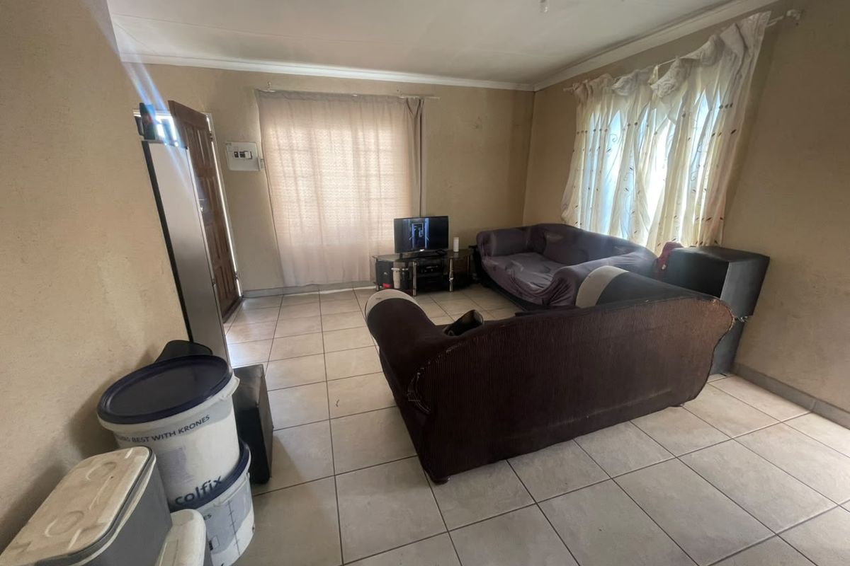 A living room featuring tiled flooring and standard cornicing, requiring cosmetic updates to the wall finishes to improve the overall aesthetic.