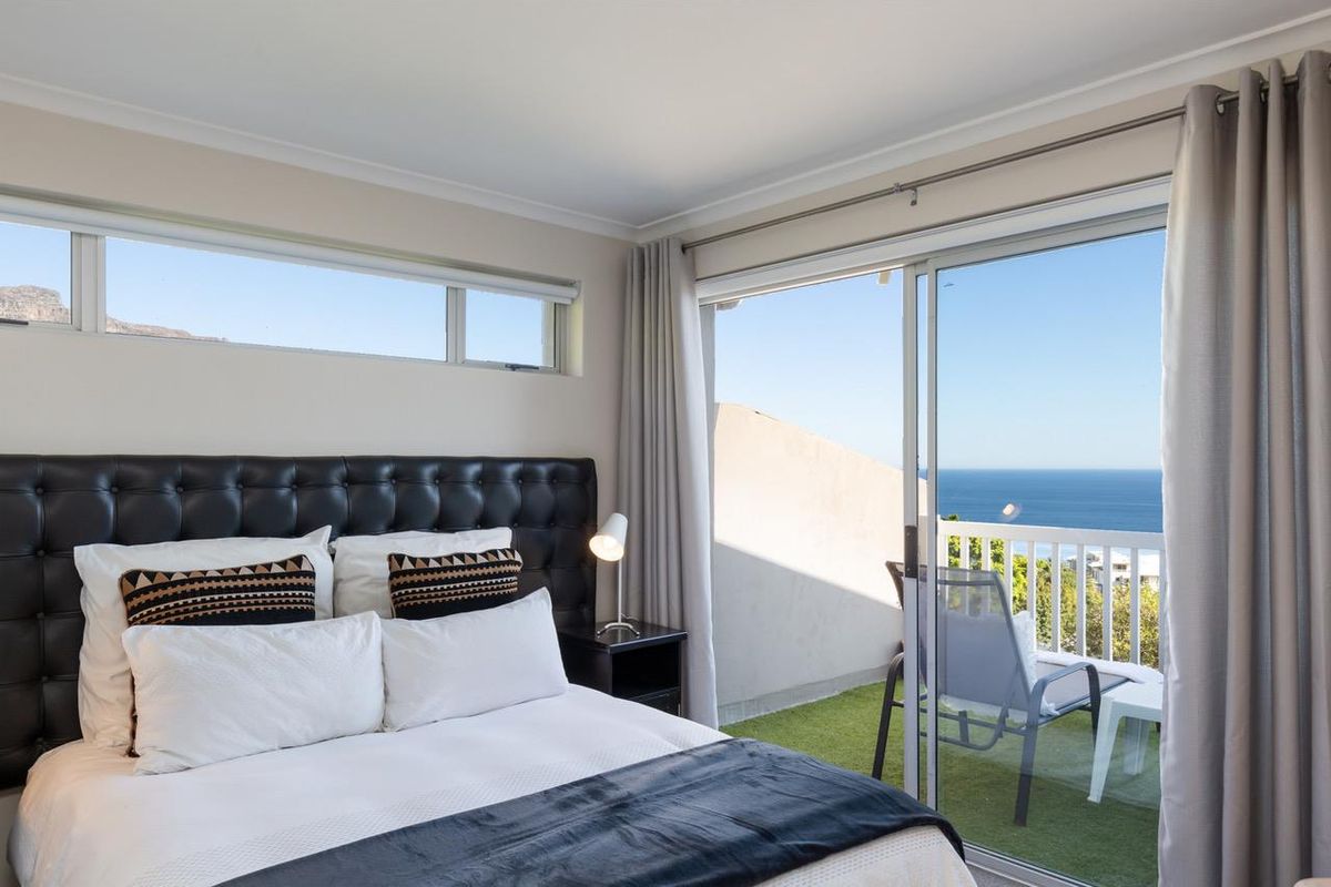 A well-maintained bedroom featuring a sliding glass door that opens onto a balcony with scenic ocean views and clerestory windows for natural light.