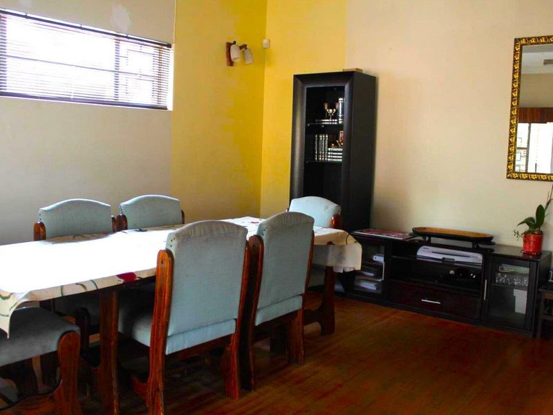 A dining room featuring timber flooring and venetian blinds, providing a functional space for meals.
