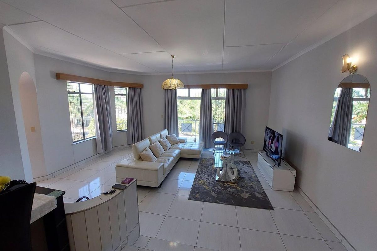 Spacious living room featuring large windows, tiled flooring, and a neutral color palette, offering a bright and open atmosphere.