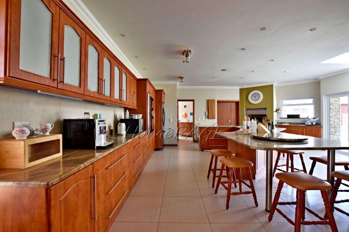 Spacious kitchen featuring extensive wooden cabinetry, granite countertops, a large central island with breakfast bar seating, and recessed ceiling lighting.