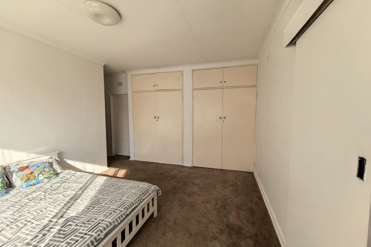 A bedroom featuring built-in cupboards with overhead storage and carpeted flooring.