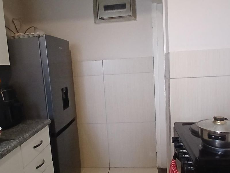 A functional kitchen area featuring built-in cabinetry, stone countertops, and tiled splashbacks, providing a practical workspace for daily cooking needs.