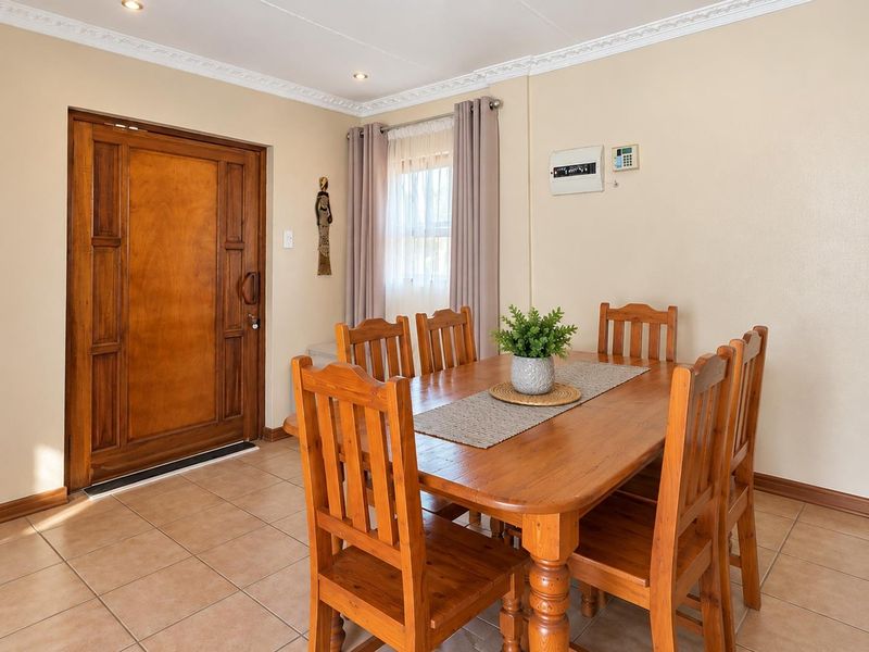 Dining area featuring ceramic floor tiles, decorative ceiling cornicing, recessed lighting, and a solid wood entrance door.