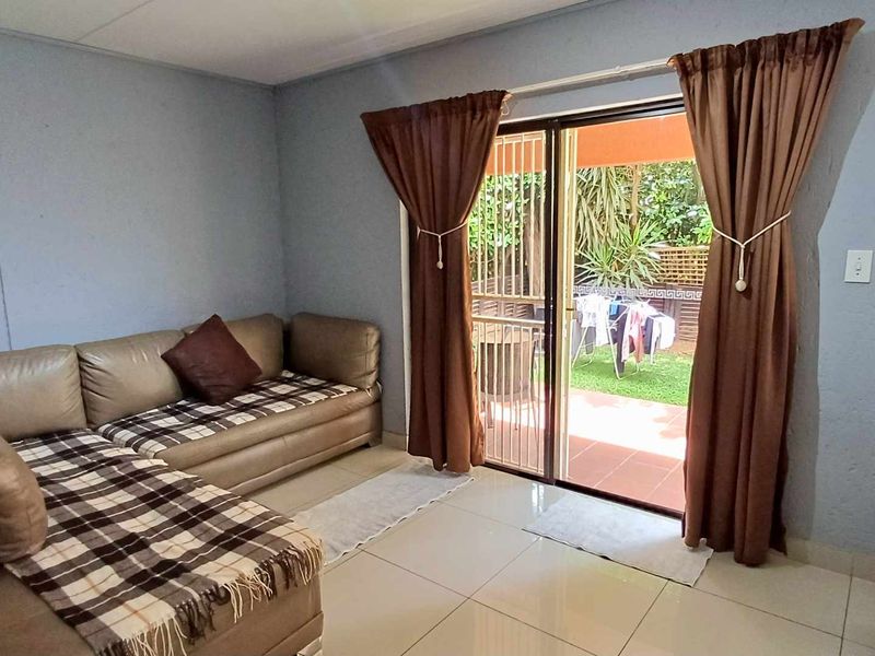 Living room featuring tiled flooring and a sliding glass door with security gate providing access to the outdoor patio area.