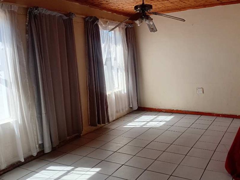 Spacious living area featuring a distinctive timber-clad ceiling, ceiling fan, and neutral ceramic floor tiles, offering a blank canvas for interior design.