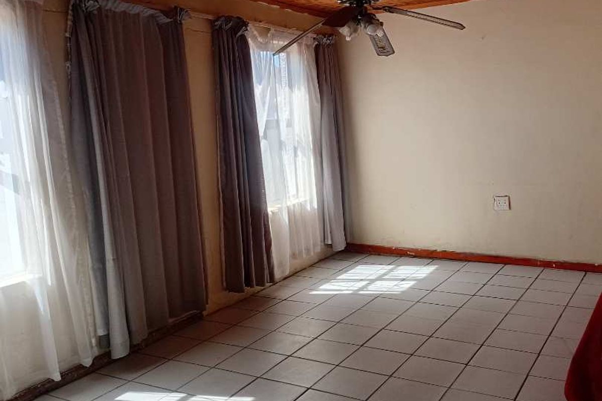 Spacious living area featuring a distinctive timber-clad ceiling, ceiling fan, and neutral ceramic floor tiles, offering a blank canvas for interior design.