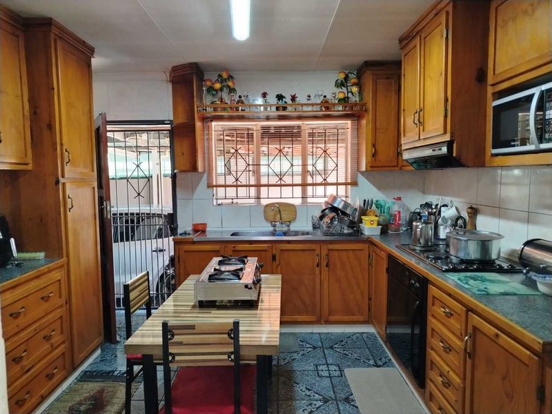 A functional kitchen featuring traditional wooden cabinetry, built-in appliances including an oven and hob, and direct access to an exterior security gate.