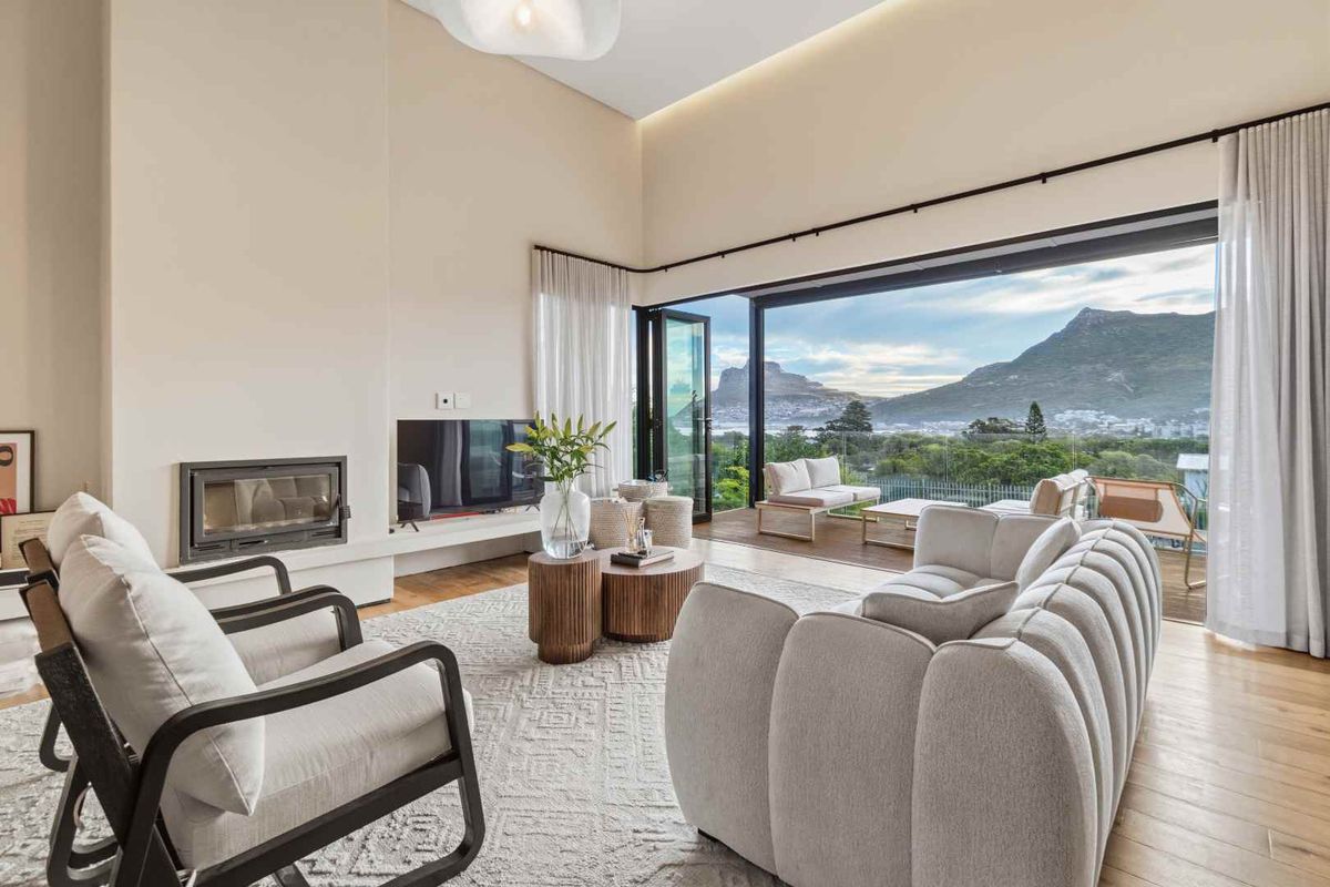 Spacious living room featuring high ceilings, a built-in fireplace, and expansive sliding doors opening to a balcony with scenic mountain and landscape views.
