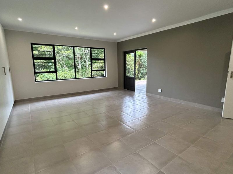 Spacious, light-filled bedroom featuring neutral tiled flooring, built-in cupboards, recessed downlights, and direct access to the outdoor area.