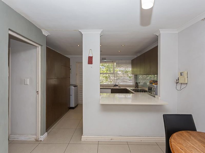 A functional kitchen featuring dark wood cabinetry, a breakfast bar, tiled flooring, and a gas hob, with an adjacent utility area.