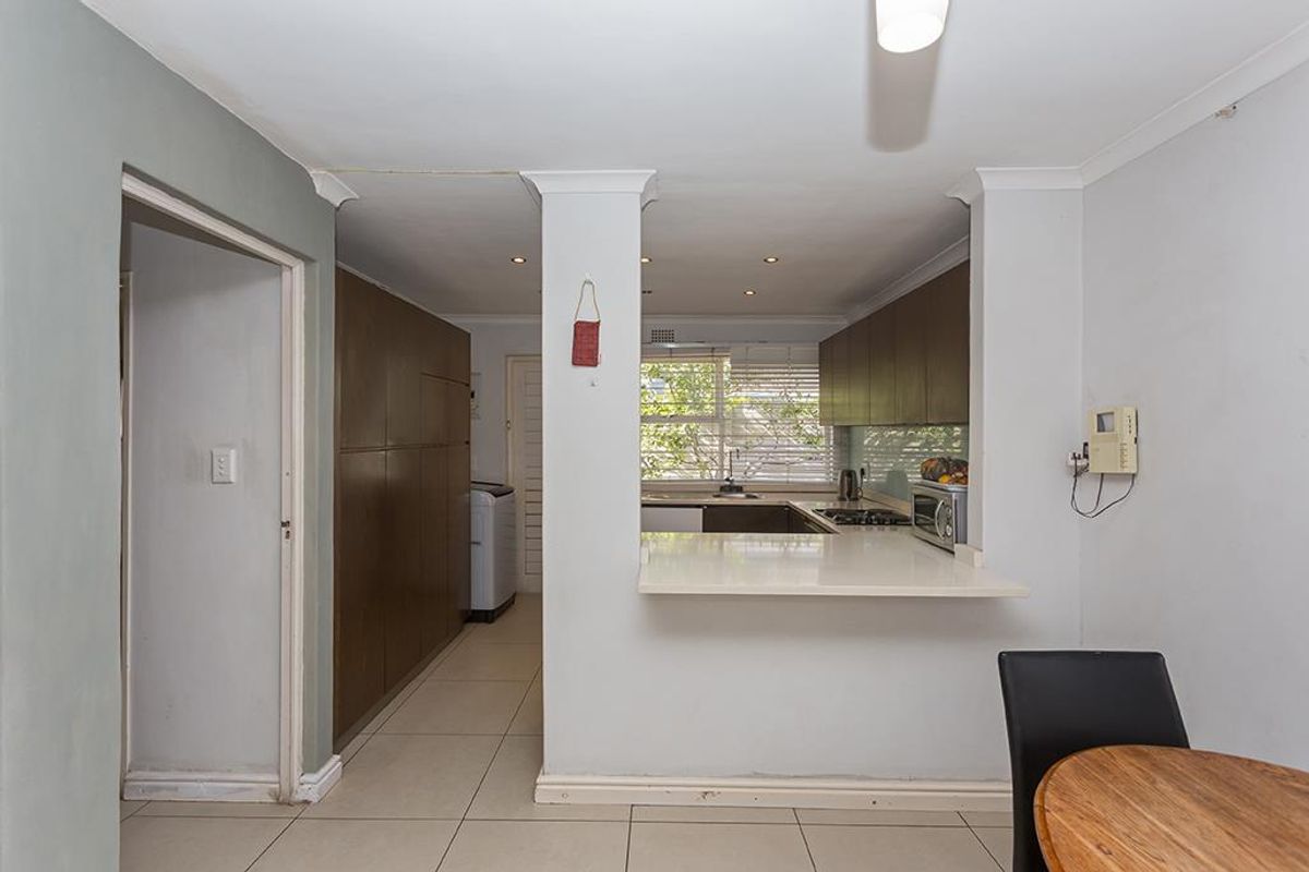 A functional kitchen featuring dark wood cabinetry, a breakfast bar, tiled flooring, and a gas hob, with an adjacent utility area.