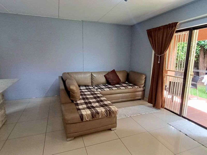 A living room featuring tiled flooring, a stone-clad breakfast bar, and a sliding glass door providing access to an outdoor patio area.