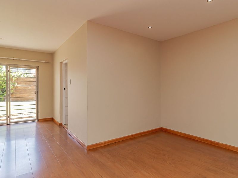 A bright, empty bedroom featuring laminate flooring, recessed lighting, and a sliding glass door providing access to the exterior.