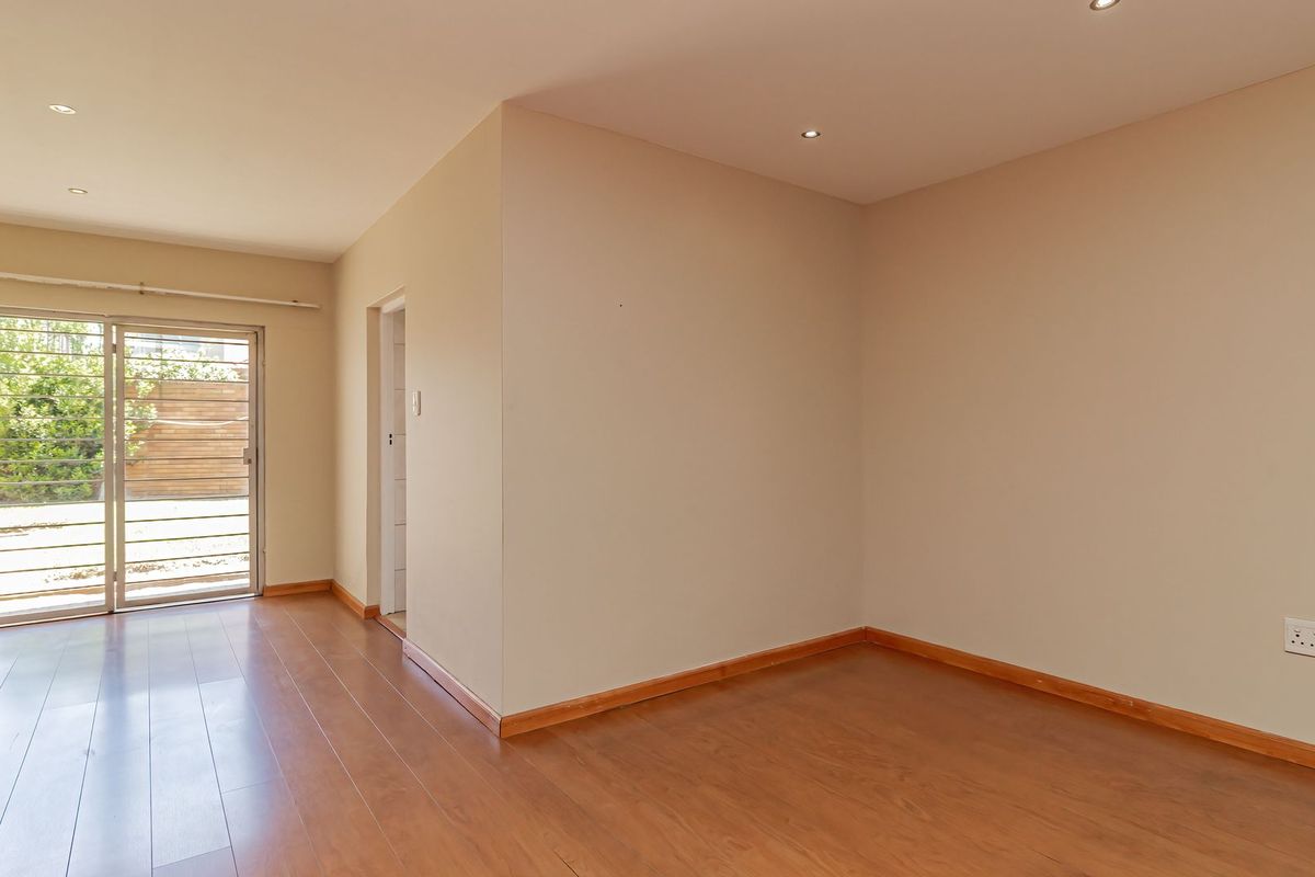 A bright, empty bedroom featuring laminate flooring, recessed lighting, and a sliding glass door providing access to the exterior.