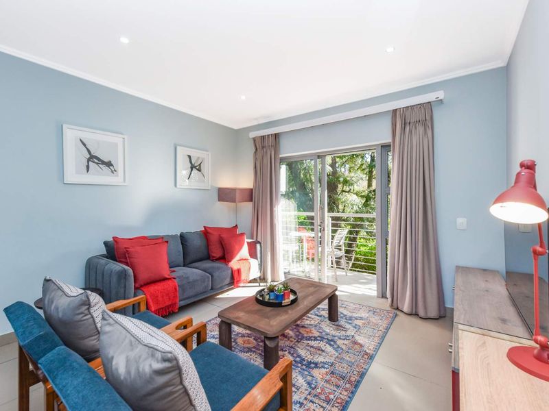 A bright living room featuring tiled flooring, recessed downlighting, and a sliding glass door providing direct access to an outdoor balcony area.