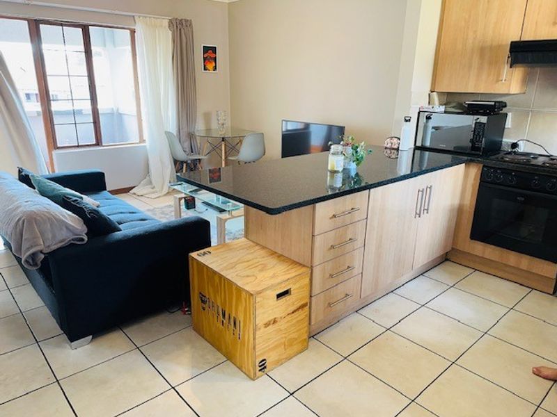 Open-plan living area featuring a kitchen with granite countertops, built-in oven, hob, and tiled flooring, seamlessly connected to the lounge space.