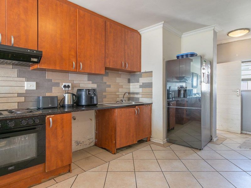 Kitchen featuring wooden cabinetry, granite countertops, built-in oven and hob, tiled backsplash, and tiled flooring. Requires maintenance to lower cabinetry.