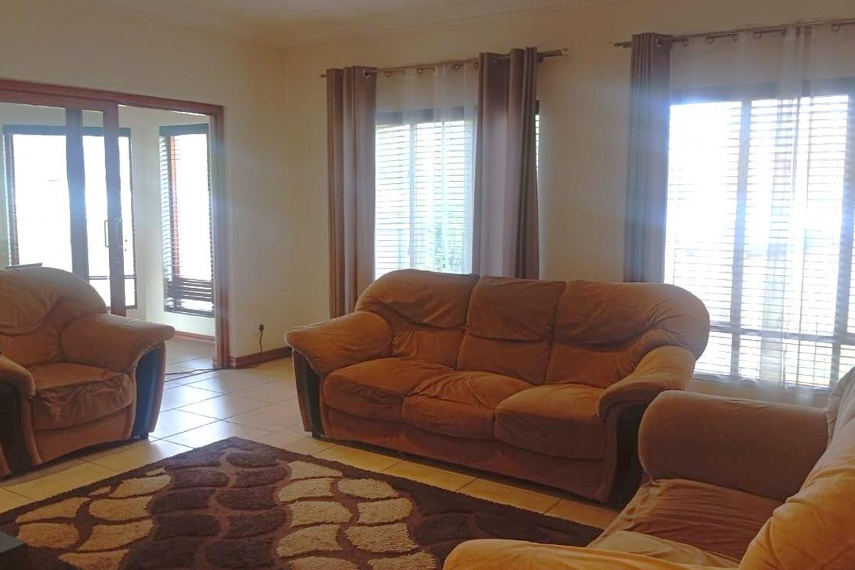 A spacious living room featuring tiled flooring, large windows with natural light, and sliding glass door access to an adjacent area.