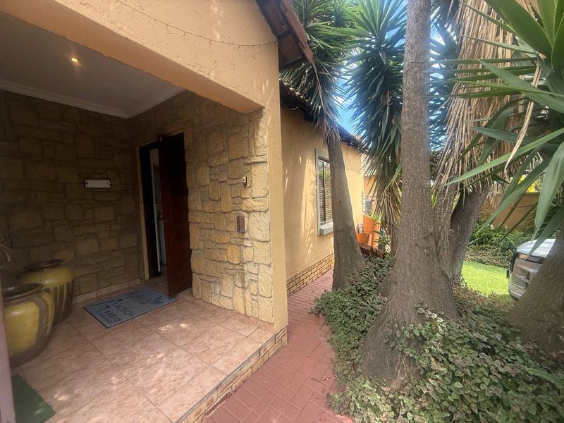 Front entrance of the townhouse featuring stone cladding, a tiled porch area, and a paved walkway leading to the front door.