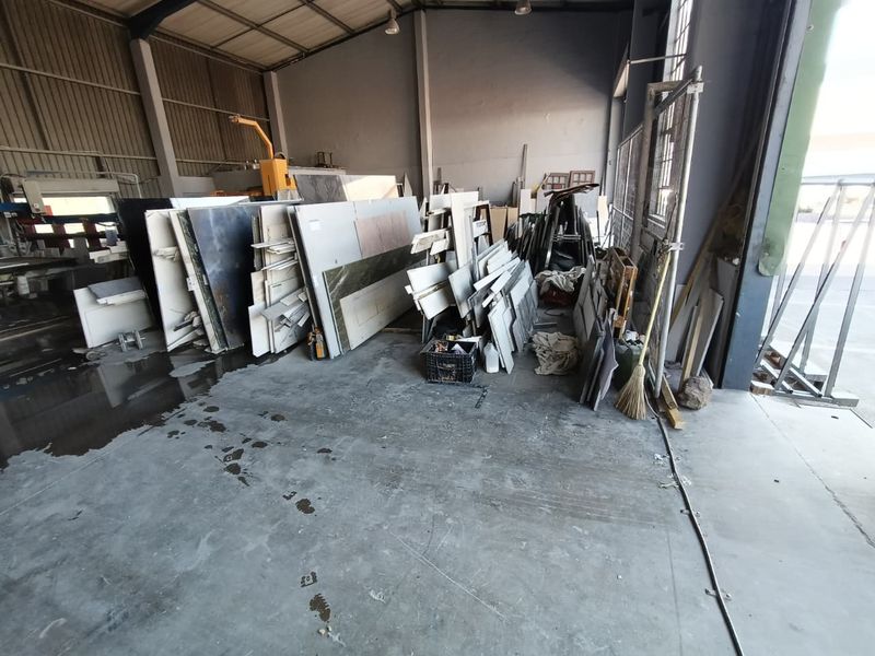 Spacious industrial utility area featuring concrete flooring, high-bay lighting, and a large roller door, suitable for manufacturing or storage operations.
