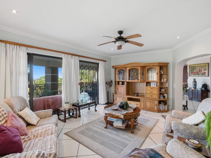 Spacious living room featuring tiled flooring, recessed ceiling lighting, a ceiling fan, and large sliding glass doors providing access to the outdoor patio area.