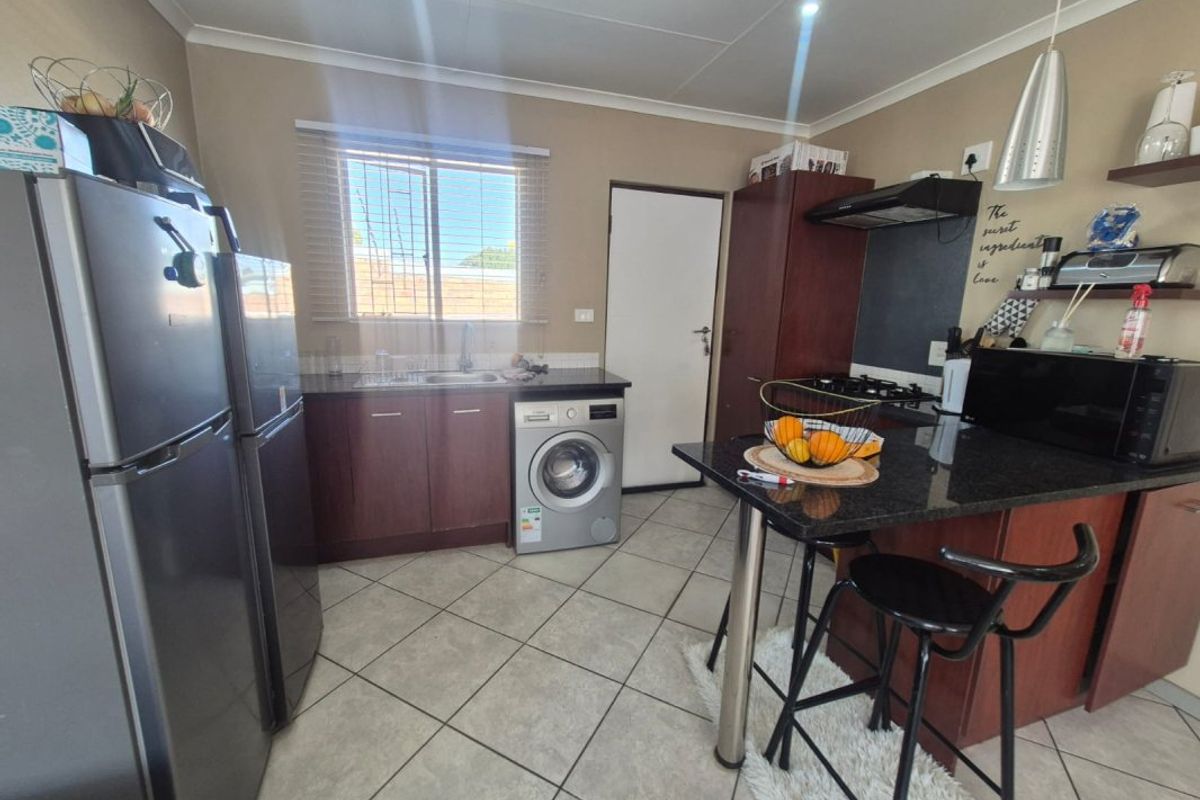 A functional kitchen featuring dark wood cabinetry, granite countertops, a gas hob with extractor fan, and tiled flooring.