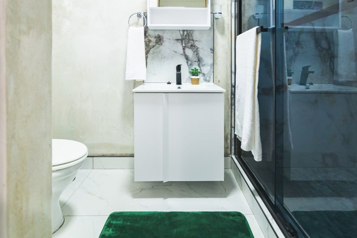 Modern bathroom featuring a vanity cabinet, marble-look splashback, and a glass-enclosed shower with tiled flooring.