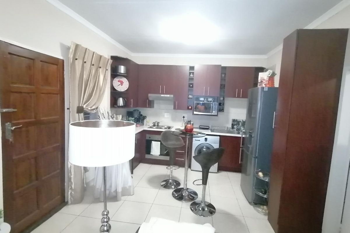 Compact kitchen featuring dark wood cabinetry, built-in oven and hob, extractor fan, and tiled flooring, providing a functional workspace.