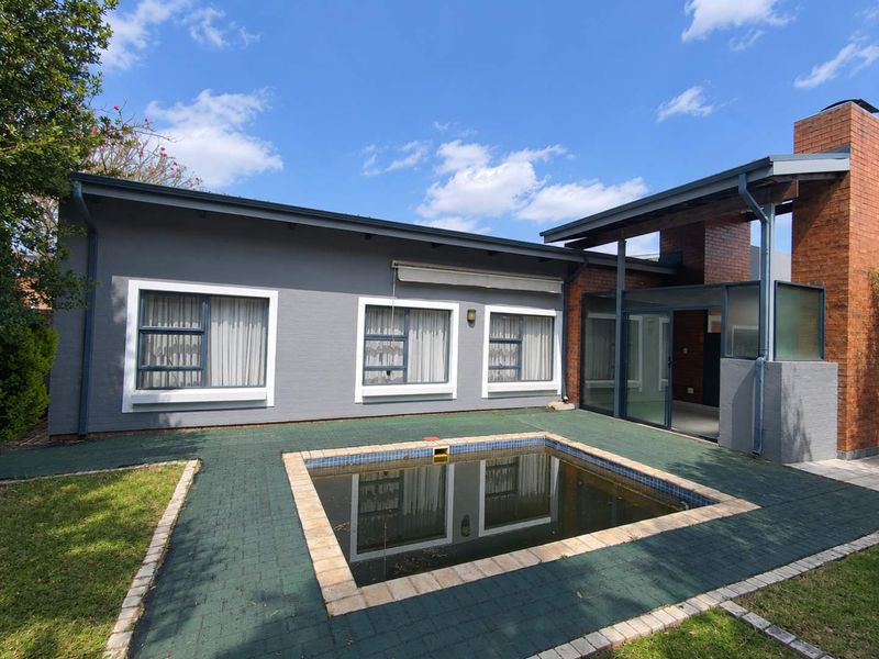 Rear exterior view of the townhouse featuring a paved patio area, a swimming pool, and a brick chimney structure.