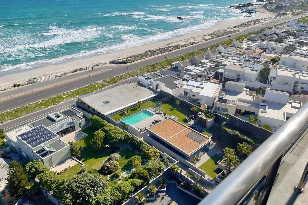 Elevated aerial view overlooking a coastal residential estate, featuring landscaped gardens, private swimming pools, and direct proximity to the oceanfront.