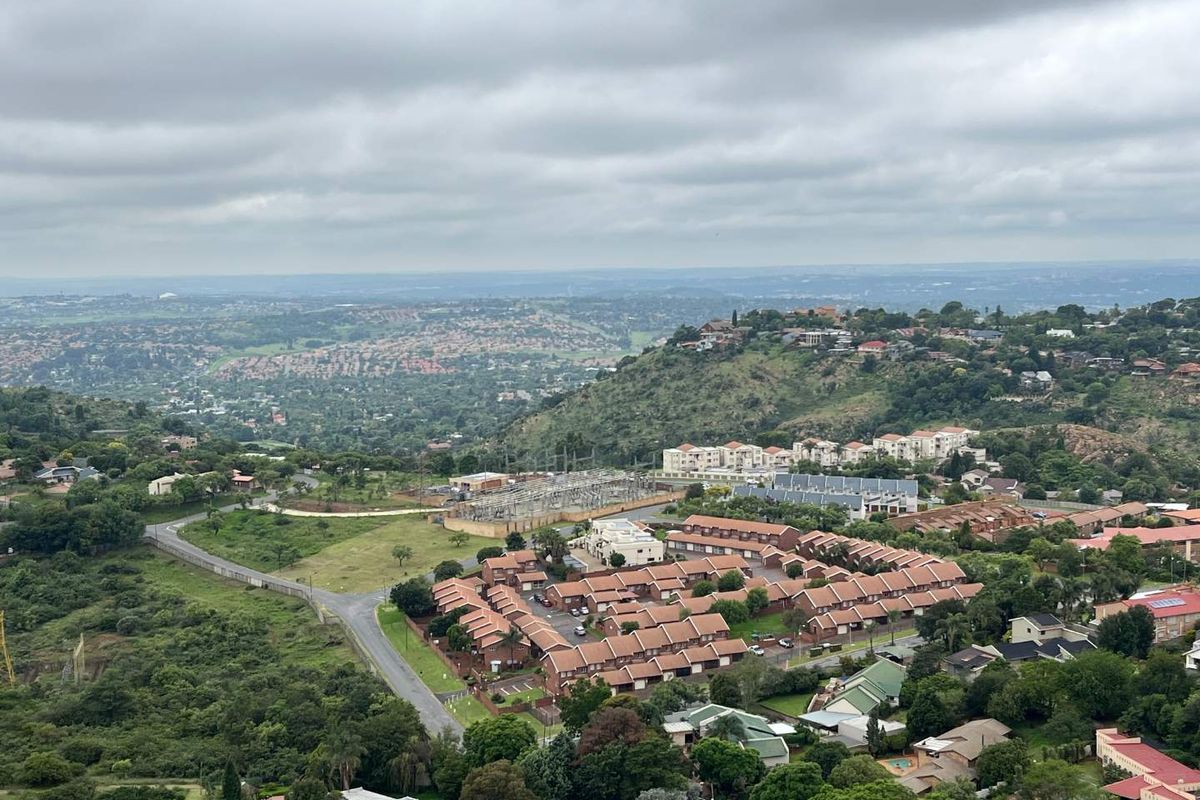 An elevated aerial view showcasing the surrounding residential neighborhood, landscape, and local infrastructure under a cloudy sky.