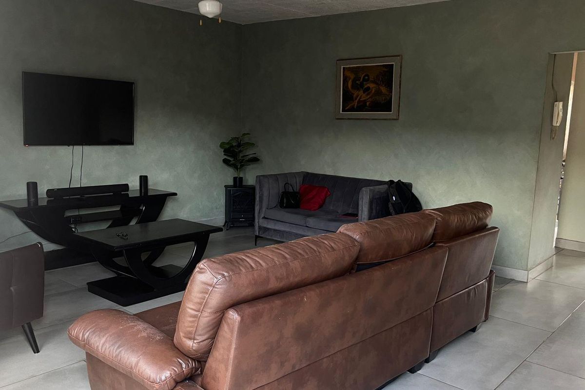 A living room featuring tiled flooring and textured green walls, providing a functional space for relaxation and entertainment.
