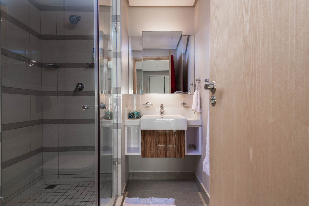 Modern bathroom featuring a glass-enclosed shower, wall-mounted vanity with integrated basin, and contemporary tiling.