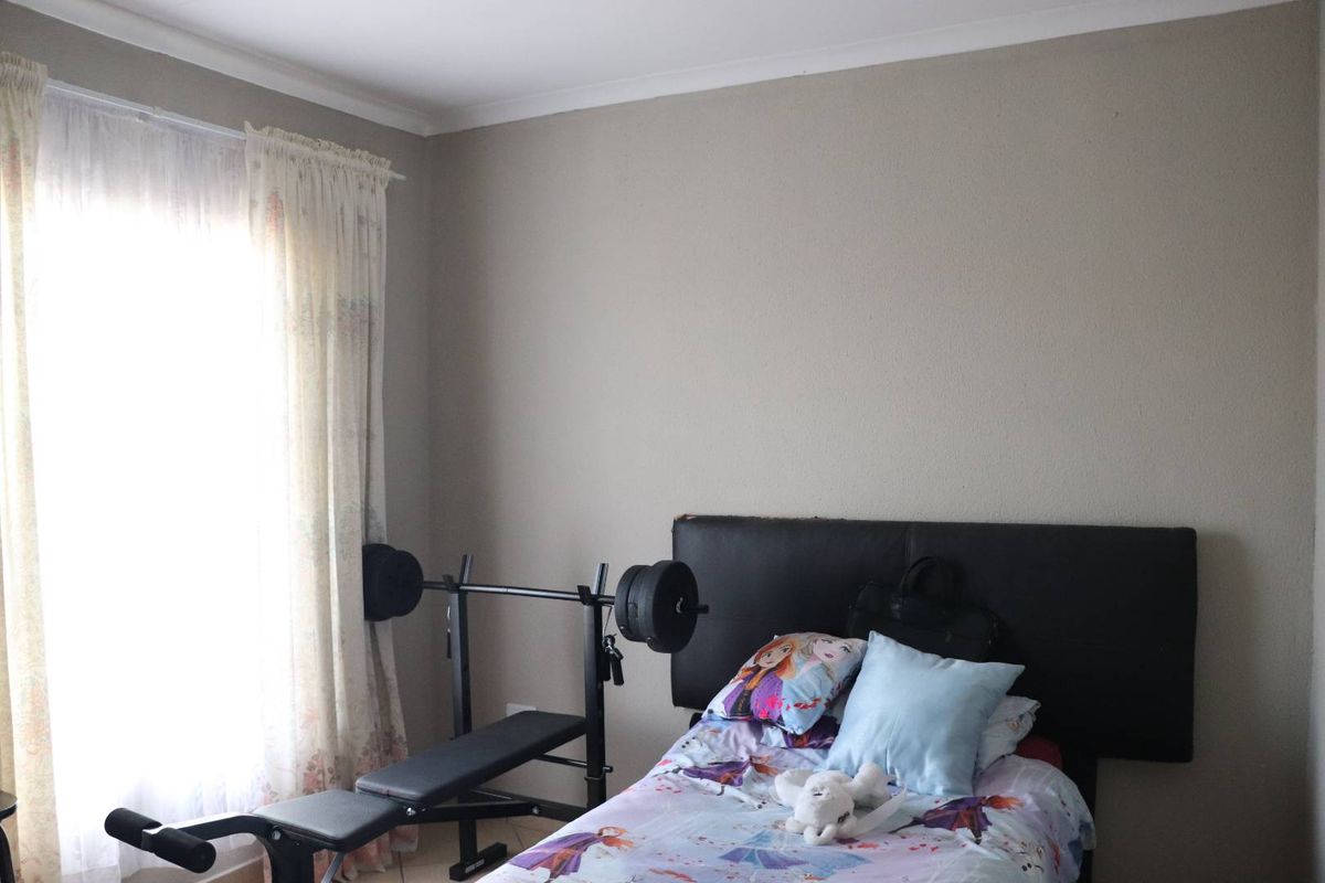 A standard bedroom featuring neutral wall paint, coving, and a window with curtains, providing a functional space for rest.