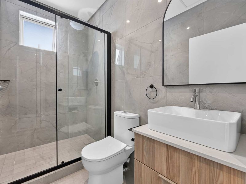 Modern bathroom featuring a glass-enclosed shower, contemporary vanity with vessel sink, and stylish grey tiled walls.