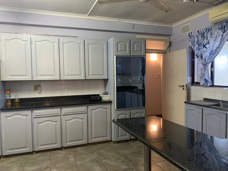 A functional kitchen featuring granite countertops, built-in cabinetry, an integrated oven, and tiled flooring, offering a practical layout with potential for modern updates.