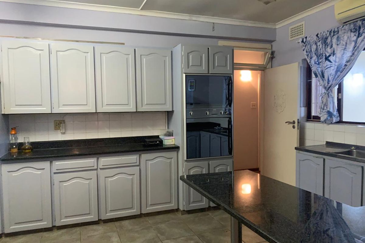 A functional kitchen featuring granite countertops, built-in cabinetry, an integrated oven, and tiled flooring, offering a practical layout with potential for modern updates.