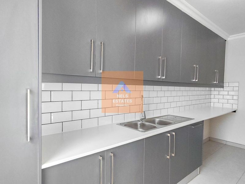 Modern kitchen featuring sleek grey cabinetry, white subway tile backsplash, and a stainless steel double sink with ample countertop space.