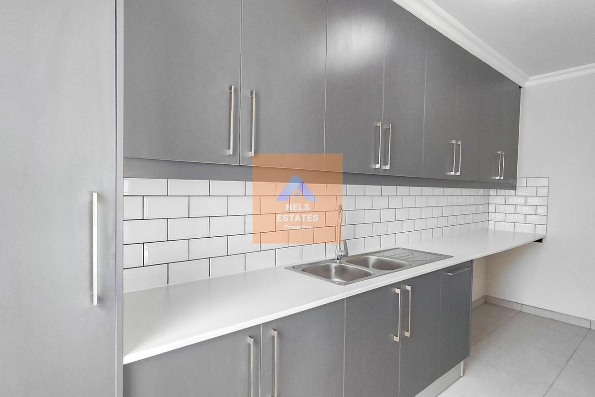 Modern kitchen featuring sleek grey cabinetry, white subway tile backsplash, and a stainless steel double sink with ample countertop space.
