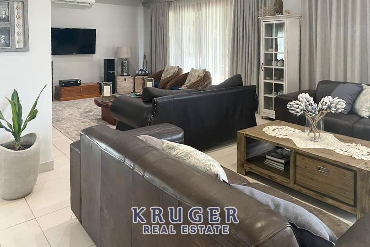 Spacious living room featuring tiled flooring, large windows with floor-to-ceiling curtains, and a wall-mounted air conditioning unit.
