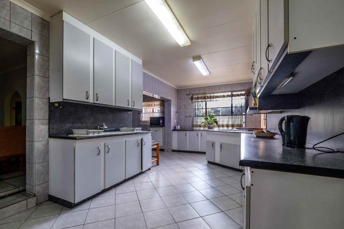 A functional kitchen featuring tiled flooring, ample cabinetry, and laminate countertops, offering a practical layout with potential for modern updates.